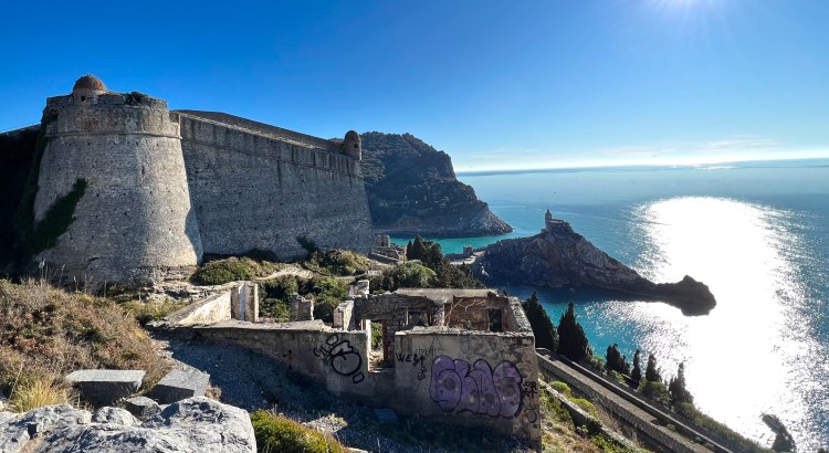 Castle wall on the left and view of church on hill on the right with water below