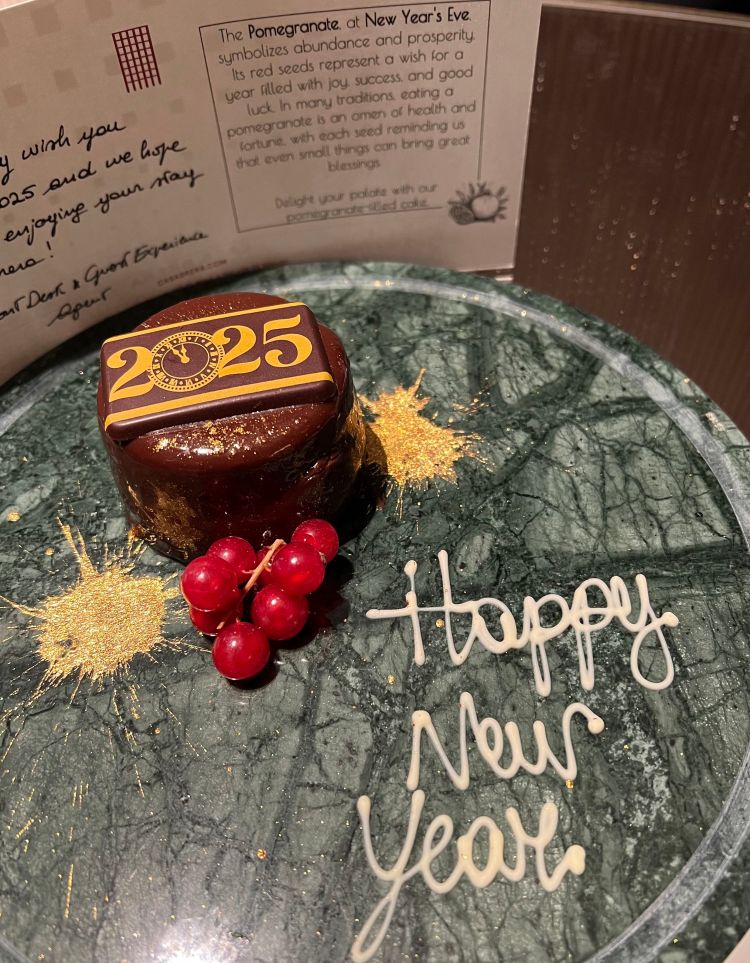 Plate with small chocolate cake with 2025 on it, and Happy New Year written on the plate