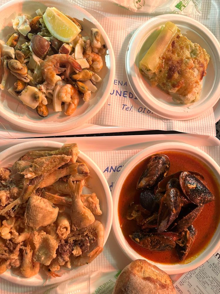 Four plates: mussels, fried fish, lasagna-like dish, and mixed seafood