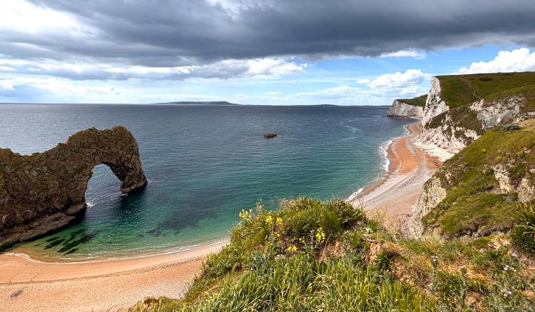 Arched rock formation on the left and white cliffs along the coast on the right