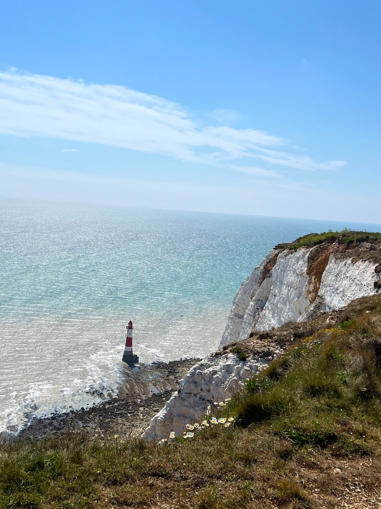 Lighthouse at the ocean level with white cliff backdrop