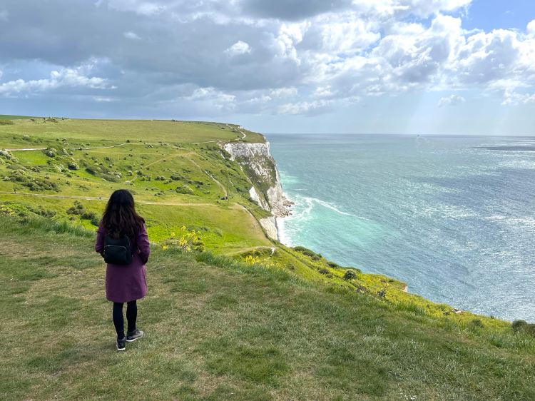 On cliffside with green grass on the left and white cliffs in distance